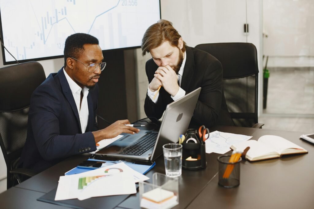 Two businessmen engaged in a strategy meeting with laptops and charts.